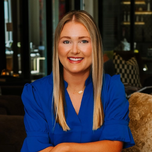 Michelle Crose professional headshot in a royal blue blouse, seated indoors with a modern office background.