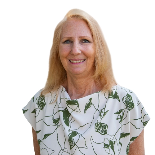 Diana Martin - WBG - 500x500 Diana professional outdoor headshot wearing a blue top and textured cardigan with greenery in the background.