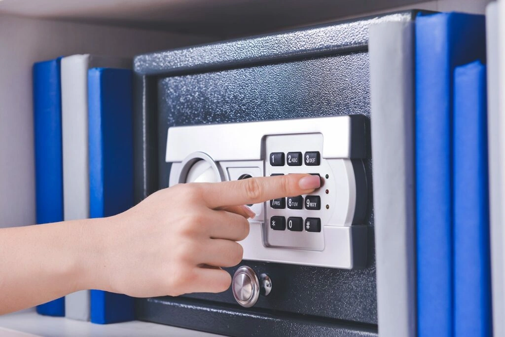 Hand entering a code into a digital safe used for storing important financial and legal documents.