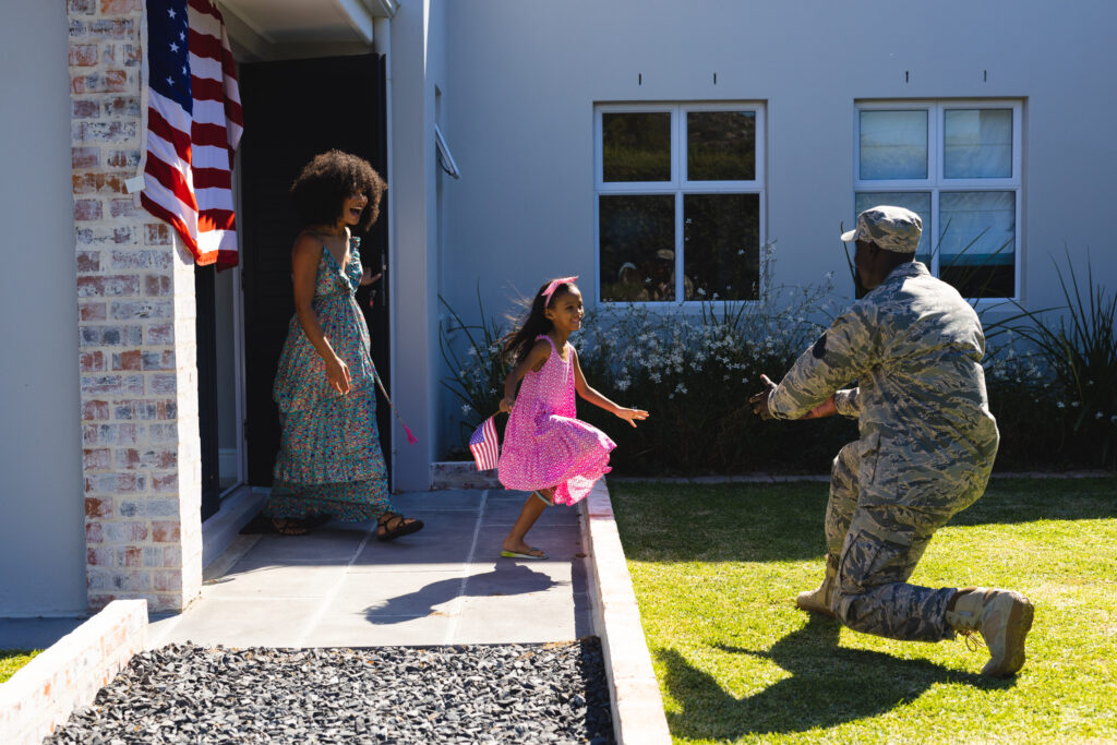 Multiracial excited woman and daughter running towards army soldier father returned home. Happy, flag of america, unaltered, family, togetherness, childhood, happy, military, patriotism, homecoming.