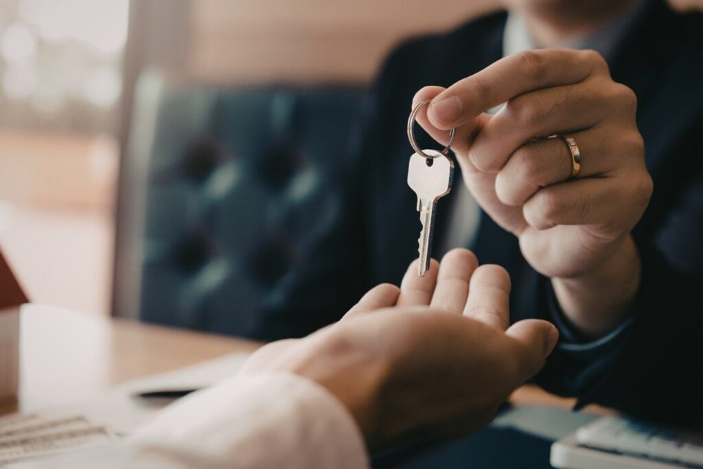Picture29 Person handing a house key to a homebuyer, symbolizing a completed home purchase and property ownership.