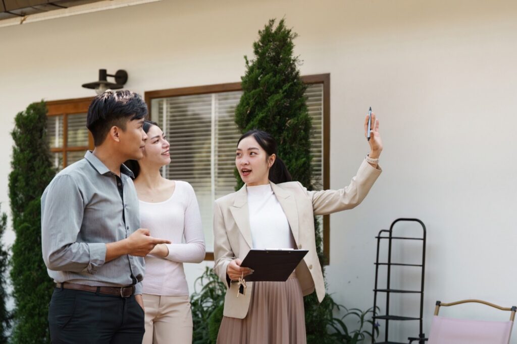 Picture59 Real estate agent showing a home to prospective buyers during a property tour, holding a clipboard outside the house.