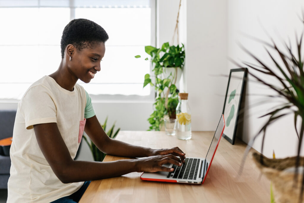 Young black woman working remotely at home using laptop computer